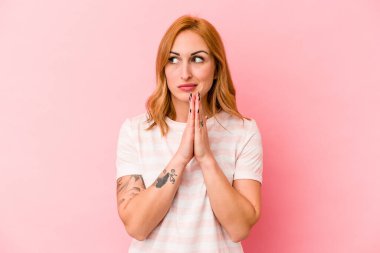Pembe arka planda izole edilmiş genç beyaz kadın dua ediyor, bağlılık gösteriyor, dindar biri ilahi ilham arıyor..