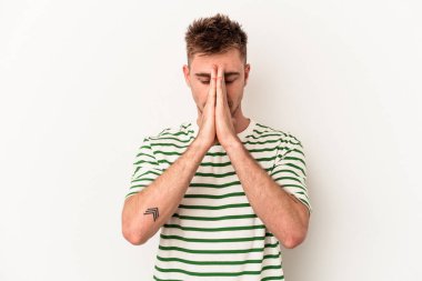 Beyaz arka planda izole edilmiş genç beyaz bir adam el ele tutuşup, ağız kenarında dua ediyor, kendinden emin..