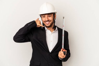 Young mixed race architect man wearing a helmet and holding meter isolated on grey background showing a mobile phone call gesture with fingers.