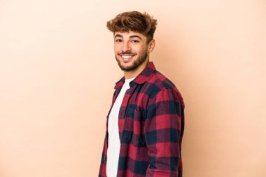 Young arab man isolated on beige background confident keeping hands on hips.