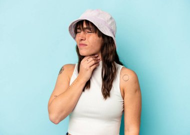 Mavi arka planda izole edilmiş genç Arjantinli kadın virüs veya enfeksiyon yüzünden boğaz ağrısı çekiyor..