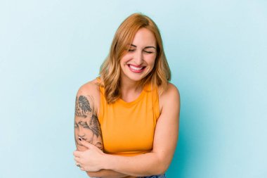 Genç beyaz kadın mavi arka planda izole edilmiş gülüyor ve eğleniyor..