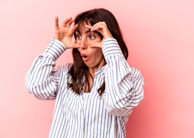 Pembe arka planda izole edilmiş genç Arjantinli kadın bir başarı fırsatı bulmak için gözlerini açık tutuyor..