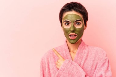 Yüz maskesi takan beyaz bir kadın. Pembe arka planda izole edilmiş. Yan tarafı gösteriyor.