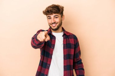 Young arab man isolated on beige background cheerful smiles pointing to front.