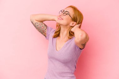 Pembe arka planda soyutlanmış genç beyaz bir kadın kendini güvende hissediyor, elleri başının arkasında..