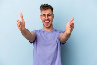 Mavi arka planda izole edilmiş genç beyaz adam kameraya sarıldığı için kendinden emin hissediyor..