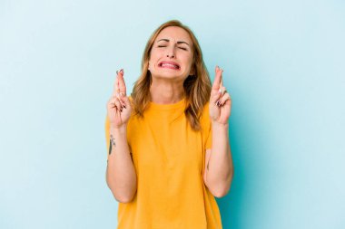 Genç beyaz kadın, mavi arka planda izole edilmiş şans dilemek için şans diliyor.