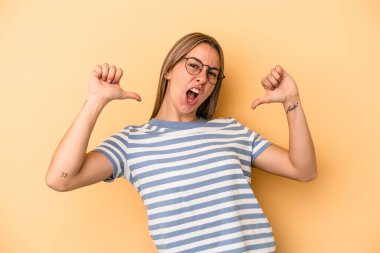 Sarı arka planda izole genç beyaz kadın gururlu ve kendinden emin hissediyor, örnek olarak..