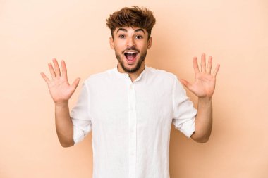 Young arab man isolated on beige background receiving a pleasant surprise, excited and raising hands.