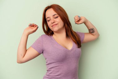 Genç beyaz kadın yeşil arka planda izole edilmiş, kollarını uzatmış, rahat bir konumda..