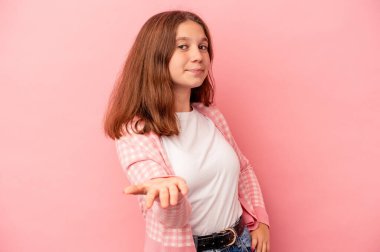 Küçük beyaz kız pembe arka planda izole edilmiş. Kameraya elini uzatıp selam veriyor..