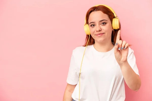 Joven Mujer Caucásica Escuchando Música Aislada Sobre Fondo Rosa Mostrando —  Fotos de Stock
