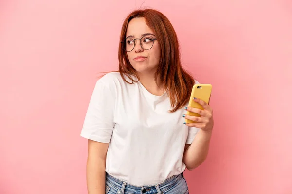 Jovem Caucasiana Segurando Telefone Celular Isolado Fundo Rosa Confuso Sente — Fotografia de Stock