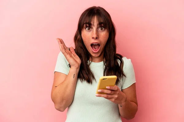 Young Argentinian Woman Holding Mobile Phone Isolated Pink Background Surprised — стоковое фото