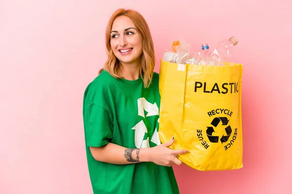 Young Caucasian Woman Recycled Plastic Isolated Pink Background Looks Aside — Stockfoto