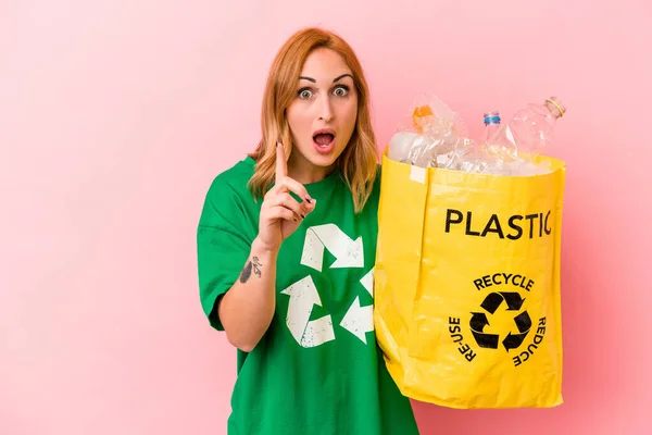 若い白人女性はピンクの背景に隔離されたプラスチックをリサイクルアイデア インスピレーションの概念を持っています — ストック写真