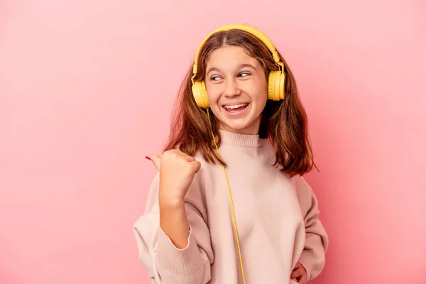 Little Caucasian Girl Listening Music Isolated Pink Background Points Thumb — стоковое фото
