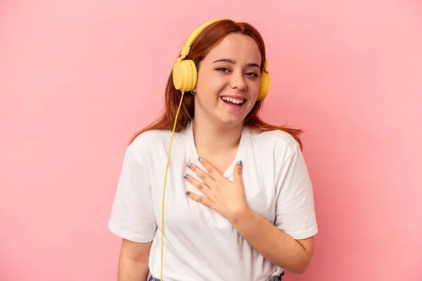 Joven Mujer Caucásica Escuchando Música Aislada Sobre Fondo Rosa Ríe —  Fotos de Stock