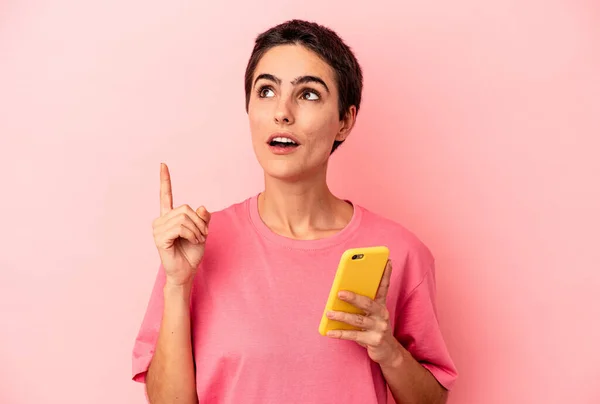 Молодая Белая Женщина Держит Мобильный Телефон Изолирован Розовом Фоне Указывая — стоковое фото