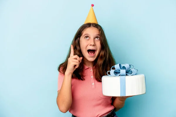 小さいですCaucasian女の子祝います彼女の誕生日保持していますケーキ孤立した上にブルー背景指しています上にオープン口 — ストック写真