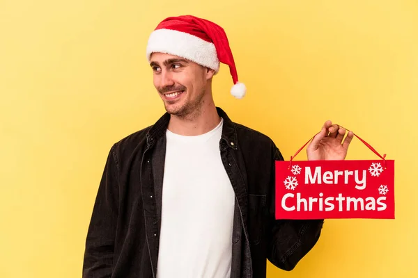 Young Caucasian Man Holding Merry Christmas Placard Isolated Yellow Background — Stock Photo, Image