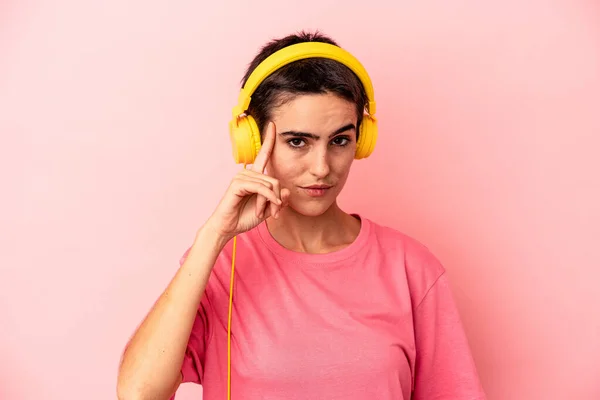 Young Caucasian Woman Listening Music Isolated Pink Background Pointing Temple — Φωτογραφία Αρχείου
