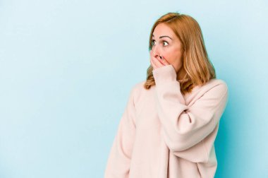 Kafkasyalı genç bir kadın mavi arka planda izole edilmiş düşünceli bir şekilde ağzıyla ağzını kapatan bir fotokopi odasına bakıyor..