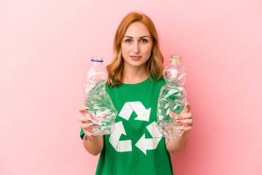 Young caucasian woman recycled plastic isolated on pink background