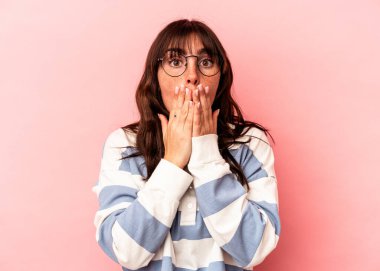 Pembe arka planda izole edilmiş genç Arjantinli kadın elleriyle ağzını kapatırken şok oldu..