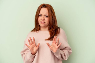 Yeşil arka planda izole edilmiş beyaz bir kadın, tiksinti belirtisi gösteren birini reddediyor..