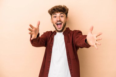 Genç Arap adam bej arka planda izole edilmiş kameraya sarıldığı için kendinden emin..