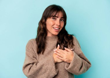 Mavi arka planda izole edilmiş genç Arjantinli kadın avuçlarını göğsüne bastıran dostça bir ifadeye sahip. Aşk konsepti.