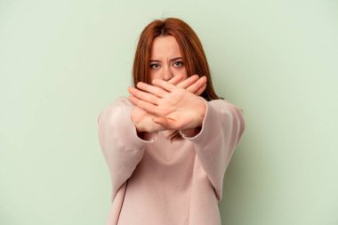 Yeşil arka planda izole edilmiş genç beyaz kadın inkar jesti yapıyor.