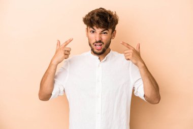 Genç Arap adam bej arka planda izole edilmiş işaret parmağıyla hayal kırıklığı jesti gösteriyor..