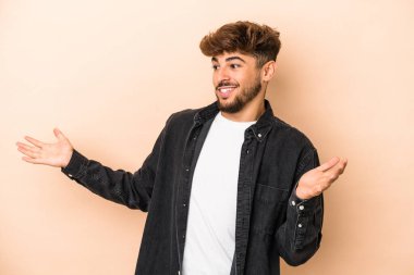 Genç Arap adam bej arka planda izole edilmiş neşeli gülüyor. Mutluluk kavramı.