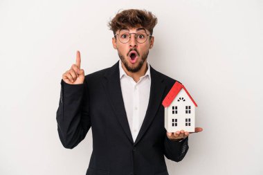 Genç Arap emlakçı izole edilmiş arka planda izole edilmiş bir model evi tutuyor. Harika bir fikri var, yaratıcılık kavramı..