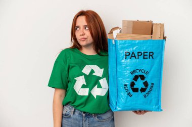 Young caucasian woman recycled paper isolated on white background confused, feels doubtful and unsure.
