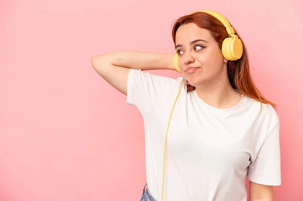 Young Caucasian Woman Listening Music Isolated Pink Background Touching Back — Φωτογραφία Αρχείου