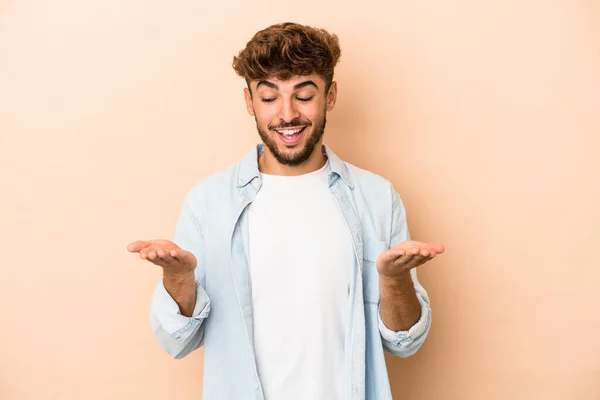 Young Arab Man Isolated Beige Background Holding Something Palms Offering — Stockfoto