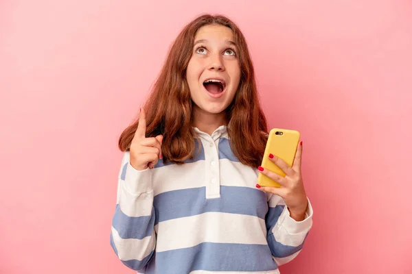 Liten Kaukasiska Flicka Som Håller Mobiltelefon Isolerad Rosa Bakgrund Pekar — Stockfoto