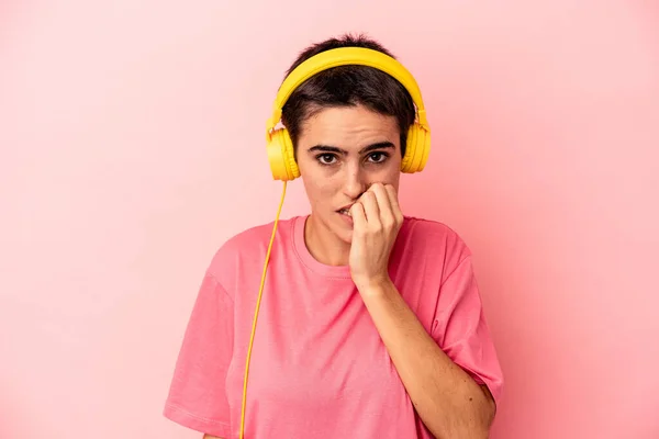 Jonge Blanke Vrouw Luisteren Naar Muziek Geïsoleerd Roze Achtergrond Bijten — Stockfoto