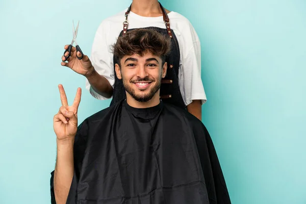 年轻的阿拉伯男子准备用手指在蓝色的背景下剪头发 — 图库照片