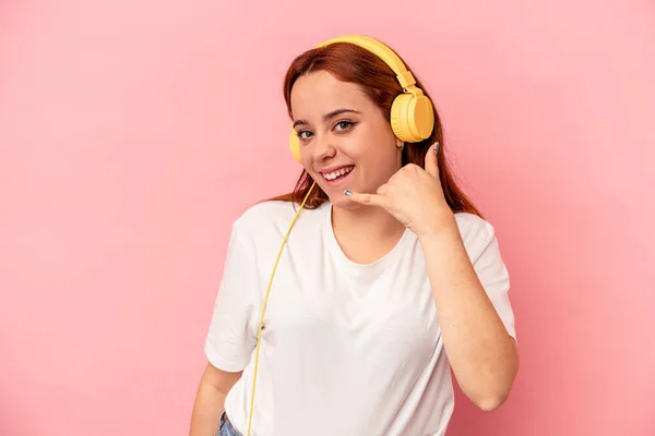 Mujer Caucásica Joven Escuchando Música Aislada Sobre Fondo Rosa Mostrando —  Fotos de Stock