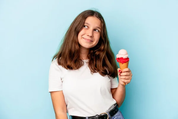 小高加索女孩吃着一个被蓝色背景隔离的冰淇淋 梦想着实现自己的目标和目的 — 图库照片
