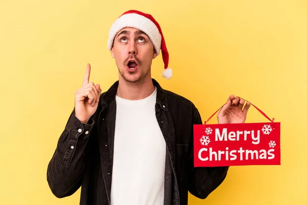 Young Caucasian Man Holding Merry Christmas Placard Isolated Yellow Background — Stock Photo, Image