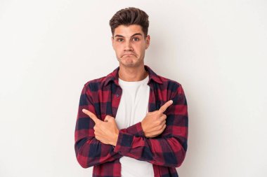 Beyaz arka plan noktalarında izole genç beyaz adam, iki seçenek arasında seçim yapmaya çalışıyor.