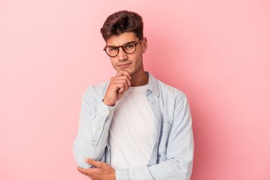 Kafkasyalı genç adam pembe arka planda izole edilmiş düşünüyor ve yukarı bakıyor, yansıtıyor, düşünüyor, bir fantezi kuruyor..