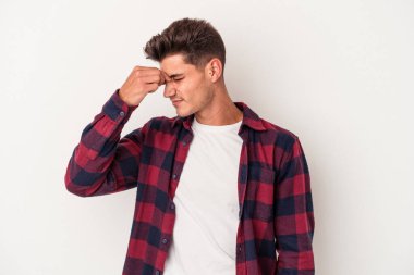Beyaz arka planda izole olmuş genç beyaz bir adam başı ağrıyor, yüzüne dokunuyor..