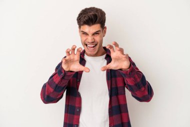 Beyaz arka planda izole edilmiş genç beyaz bir adam pençelerini kedi taklidi yaparken gösteriyor, agresif bir hareket..